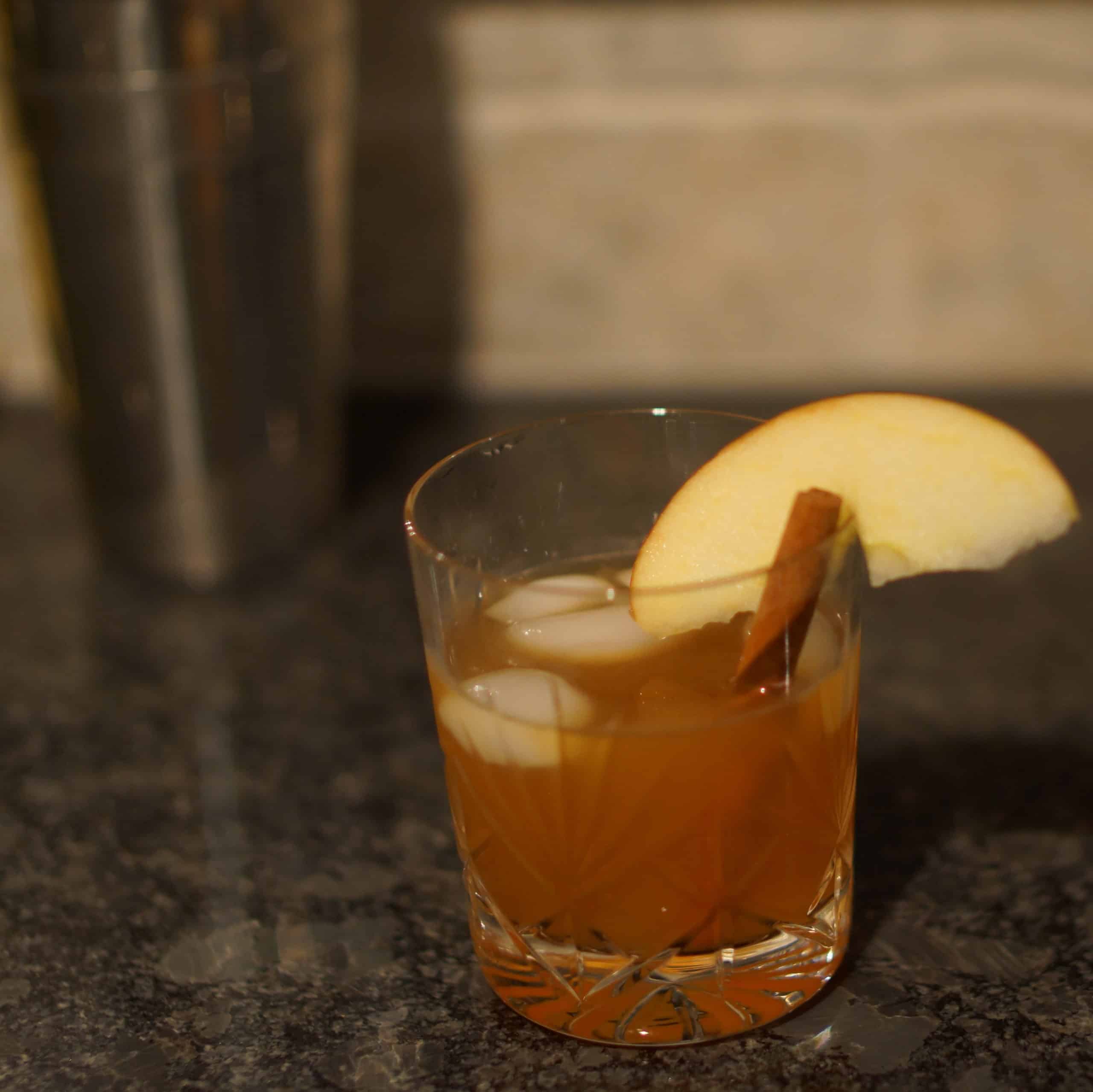 Bourbon and apple cider cocktail with a cinnamon stick and apple slice.