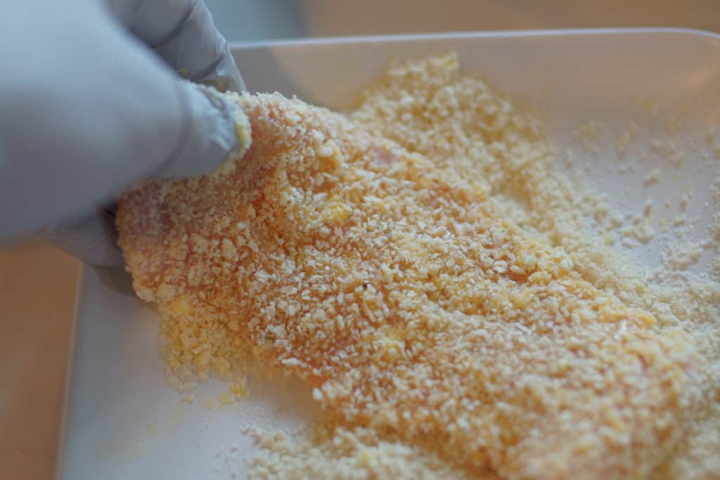 Veal cutlets being breaded.