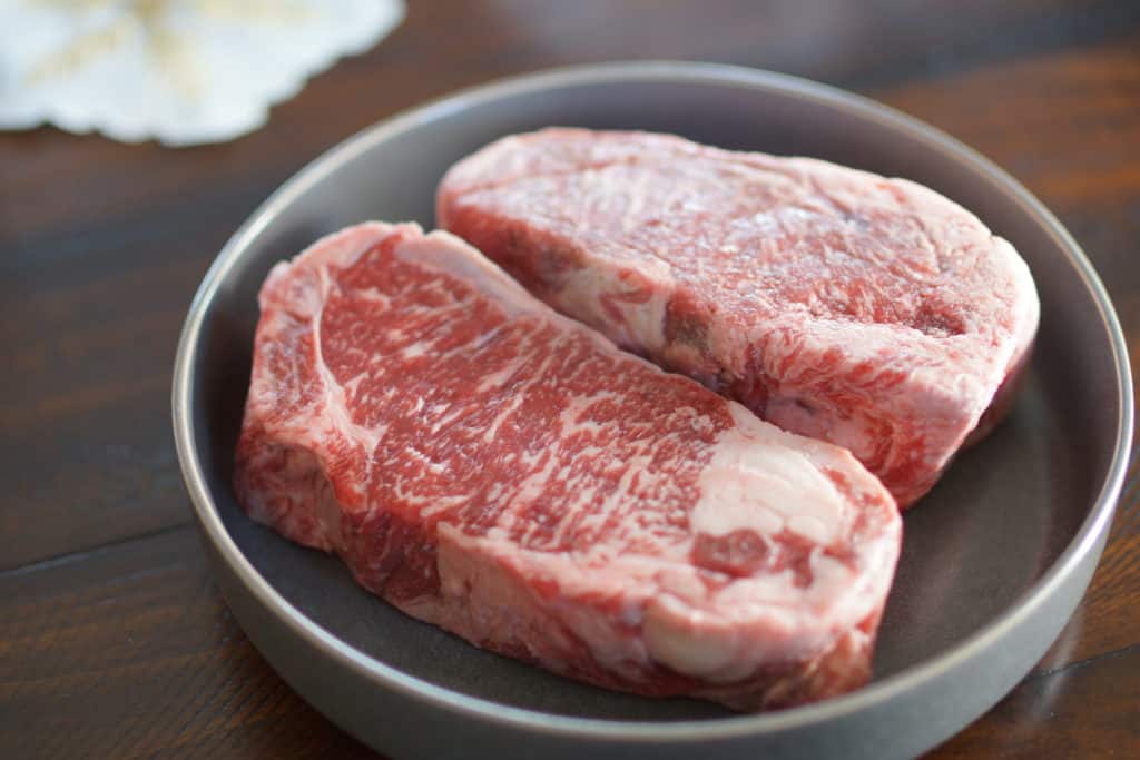 Uncooked New York Strip steaks on a plate