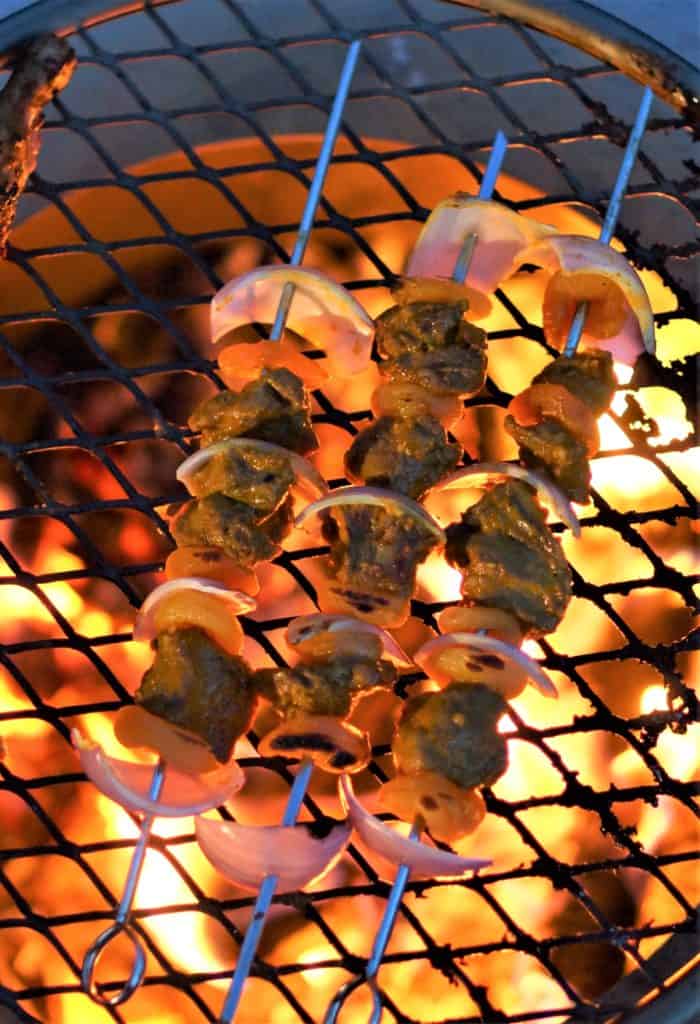 Lamb and apricot sosaties cooking over a live fire.