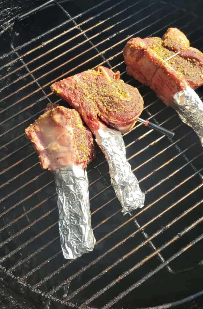 Beef short rib tomahawks smoking on a barrel smoker.