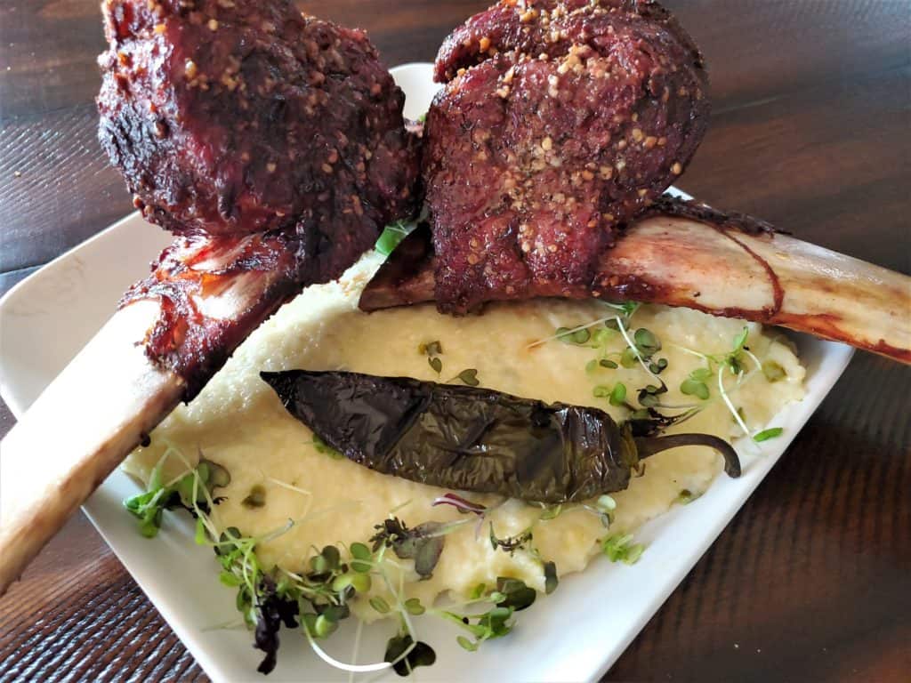 Beef Short rib tomahawks served over Cheesy Jalapeno Grits
