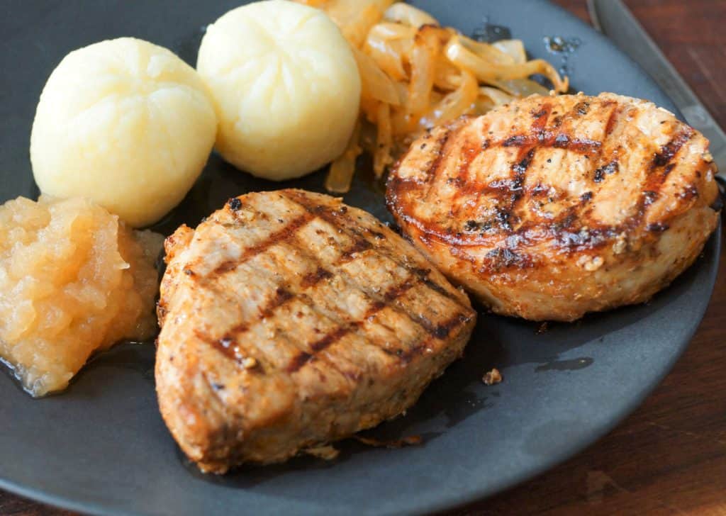 Grilled German Pork chops on a black plate.