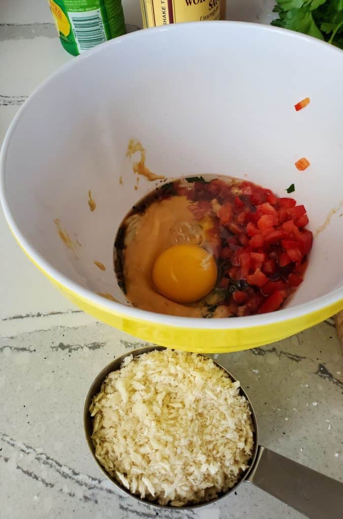 Egg, red bell pepper and other ingredients in a bowl.