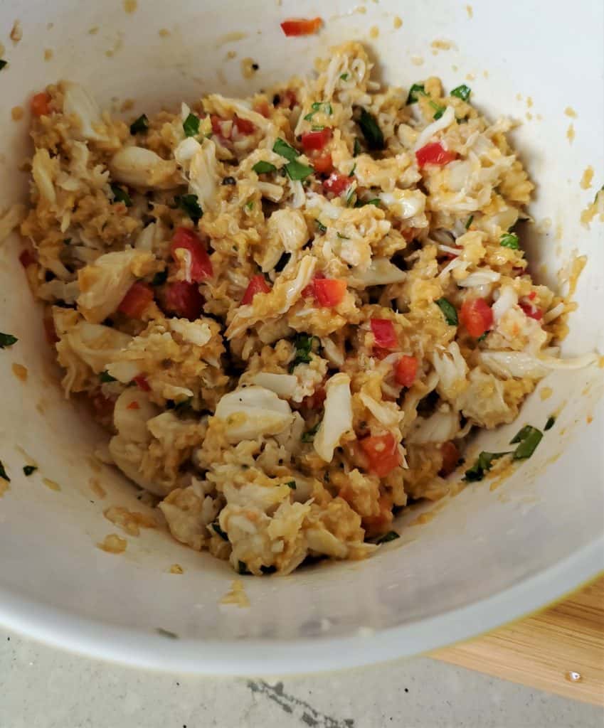 Lump crab meat in a bowl mixed with egg, bell pepper, and other ingredients.