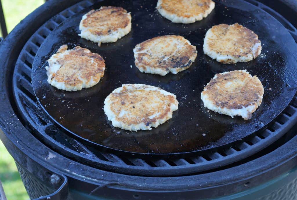 Fried Mashed Potato cakes cooking on a griddle.