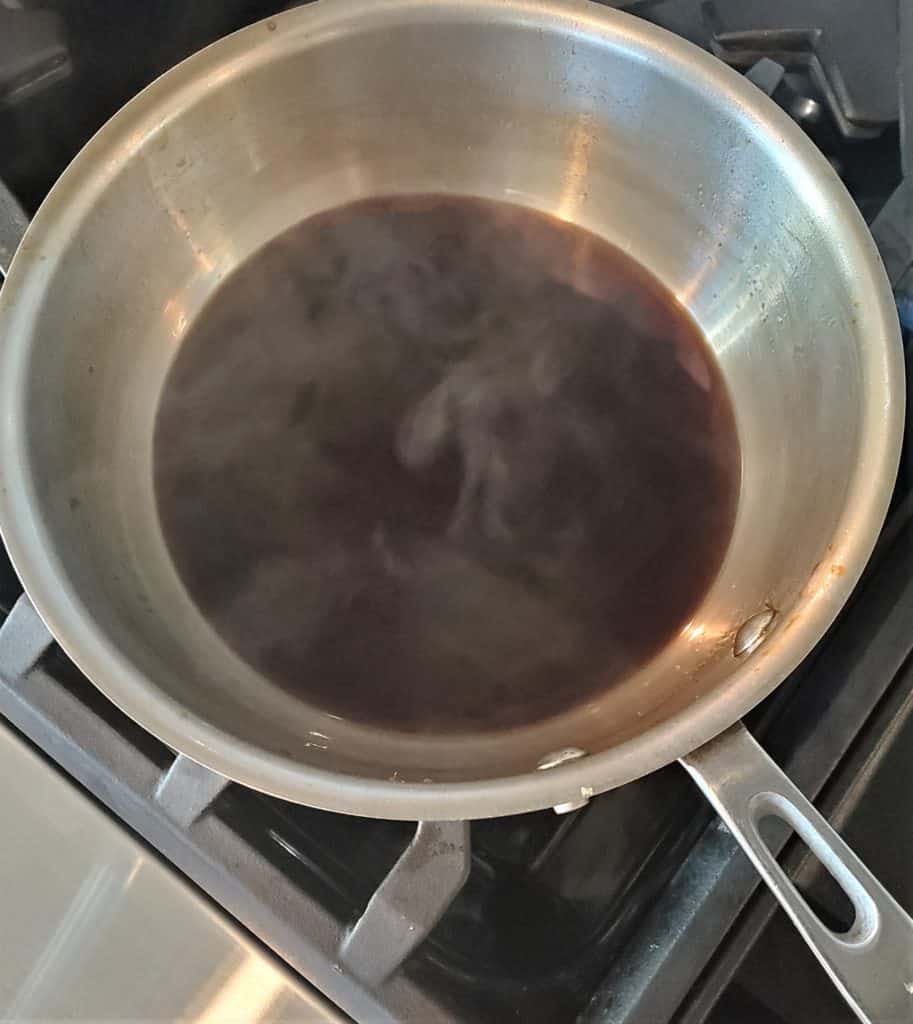 Root beer ham glaze reducing in a sauce pan.