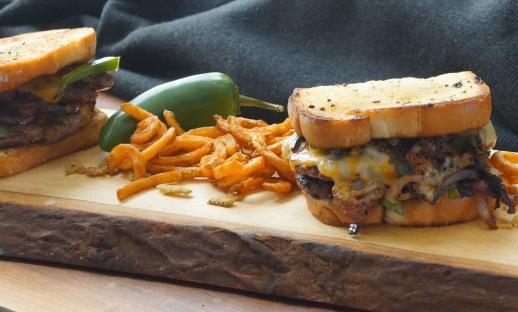 Spicy Double Smash Burger with Jalapenos and Texas Toast, served on a wood plank with fries.