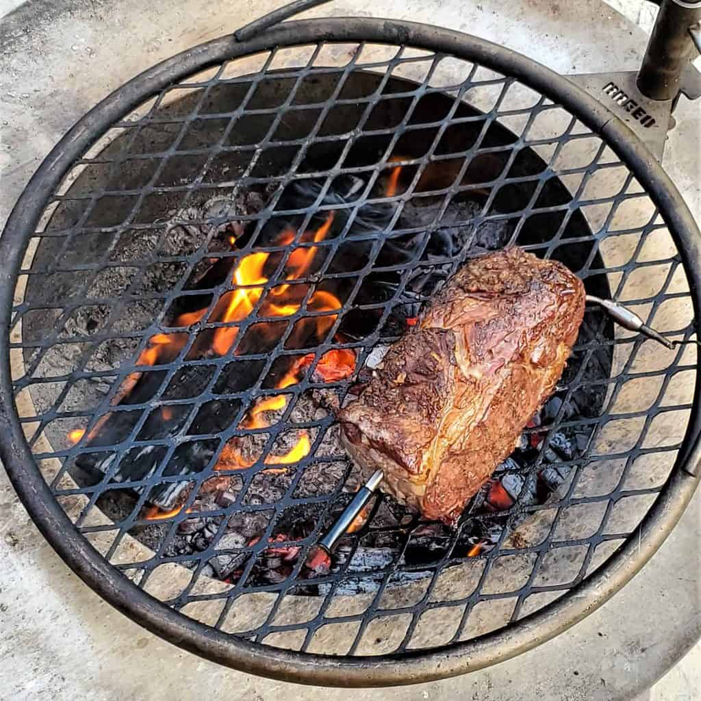 Ribeye roast cooking over and open live fire.