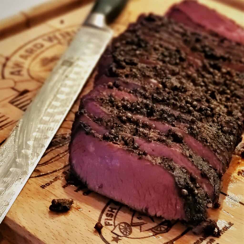 Smoked pastrami sliced on a cutting board.