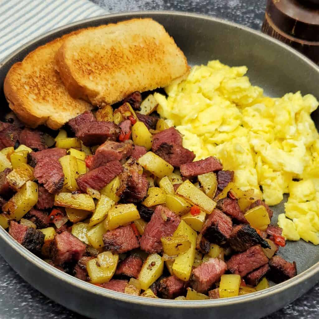 Plate of smoked corned beef hash with scrambled eggs and toast.s