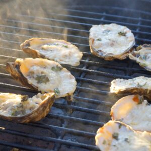 Chargrilled oysters cooking on a Big Green Egg.