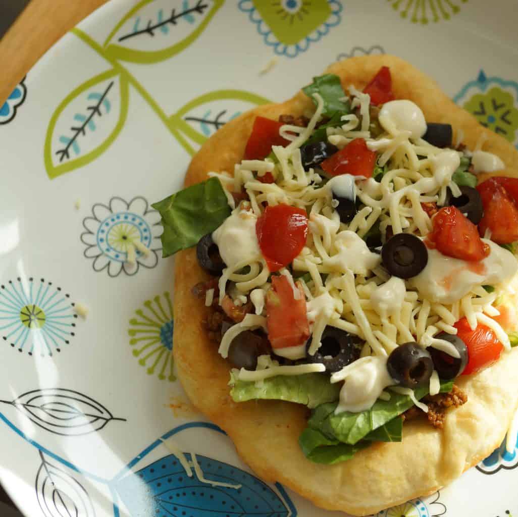 Navajo frybread taco topped with seasoned beef, black olives, tomato, cheese, lettuce and sour cream.