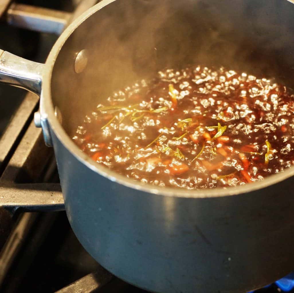 Herbs simmering in a pan with beef broth.