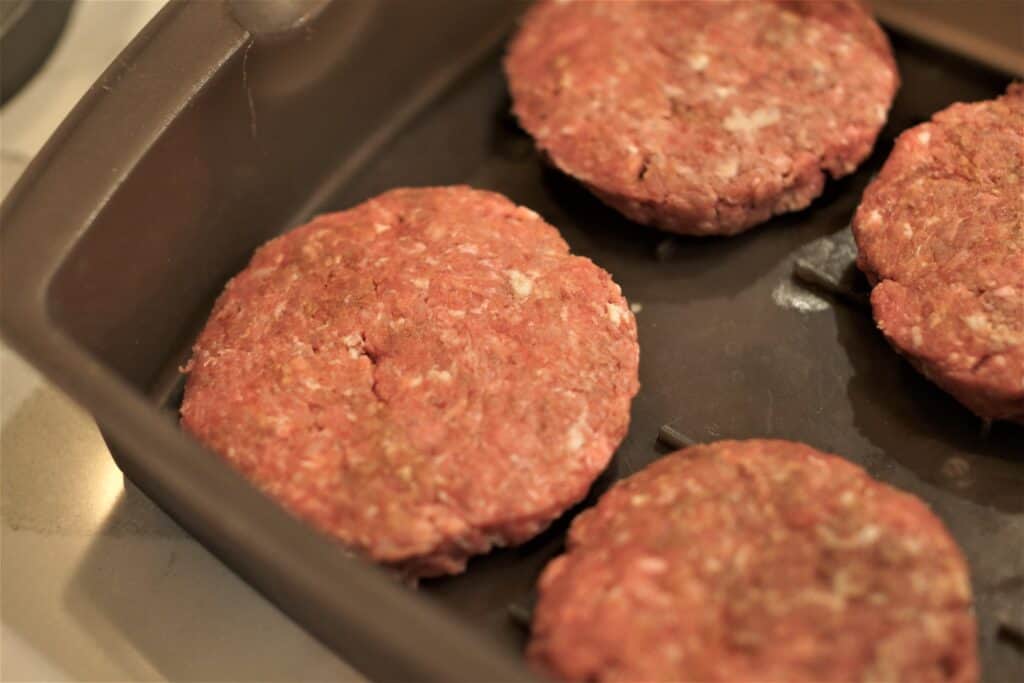 Hamburger patties in a pan.
