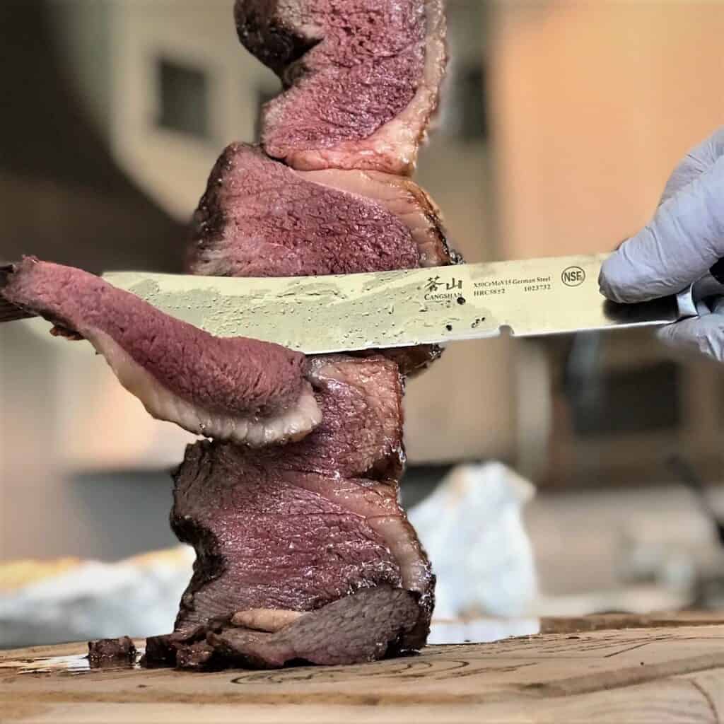 Rotisserie Picanha being sliced of a skewer.