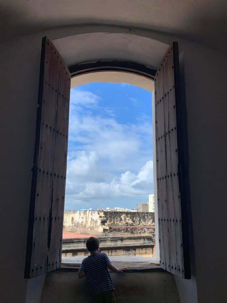 Boy peering out a window at Old San Juan.