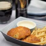Beer battered cod with fries and tarter sauce in front of a glass of Guinness