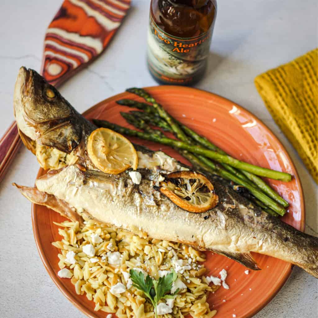 Stuffed grilled branzino served with orzo and a bottle of beer.