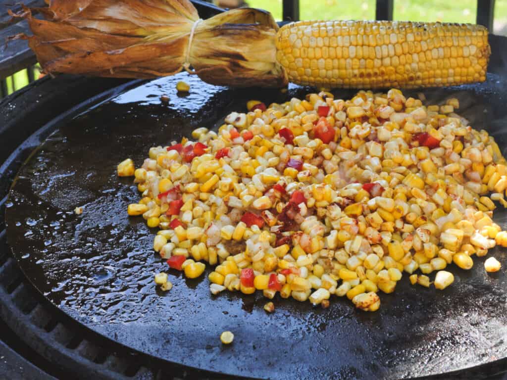 Corn and peppers cooking on a Cooking Steel griddle on a Big Green Egg.