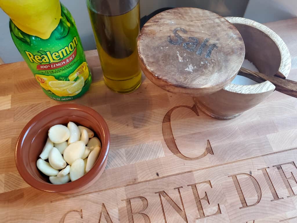 Lemon, garlic, salt and olive oil on a cutting board
