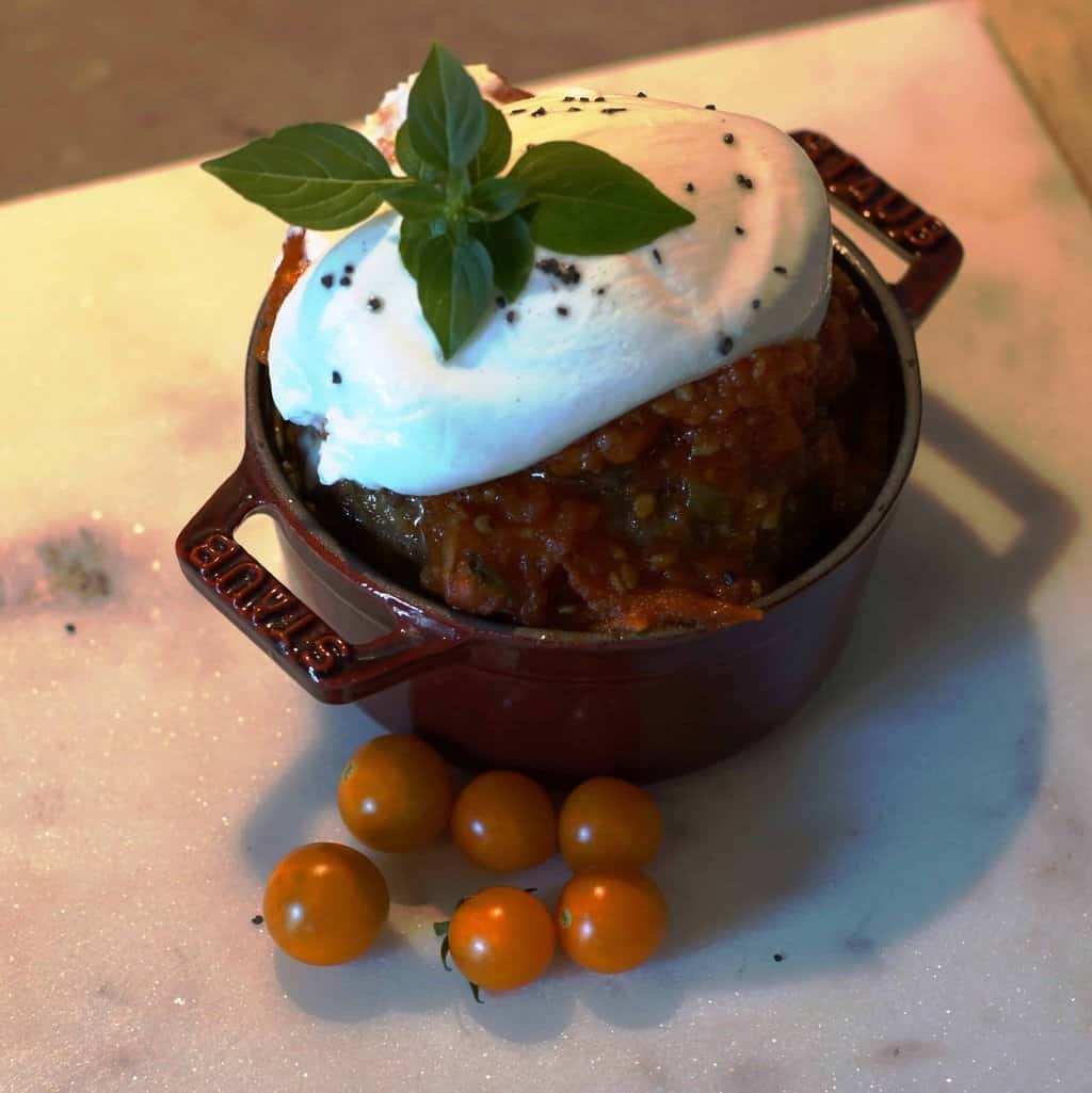 Ramekin with a large meatball topped with marinara, burrata and basil.