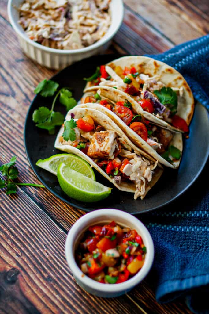 Plate of spicy mahi mahi fish tacos on a wood table.