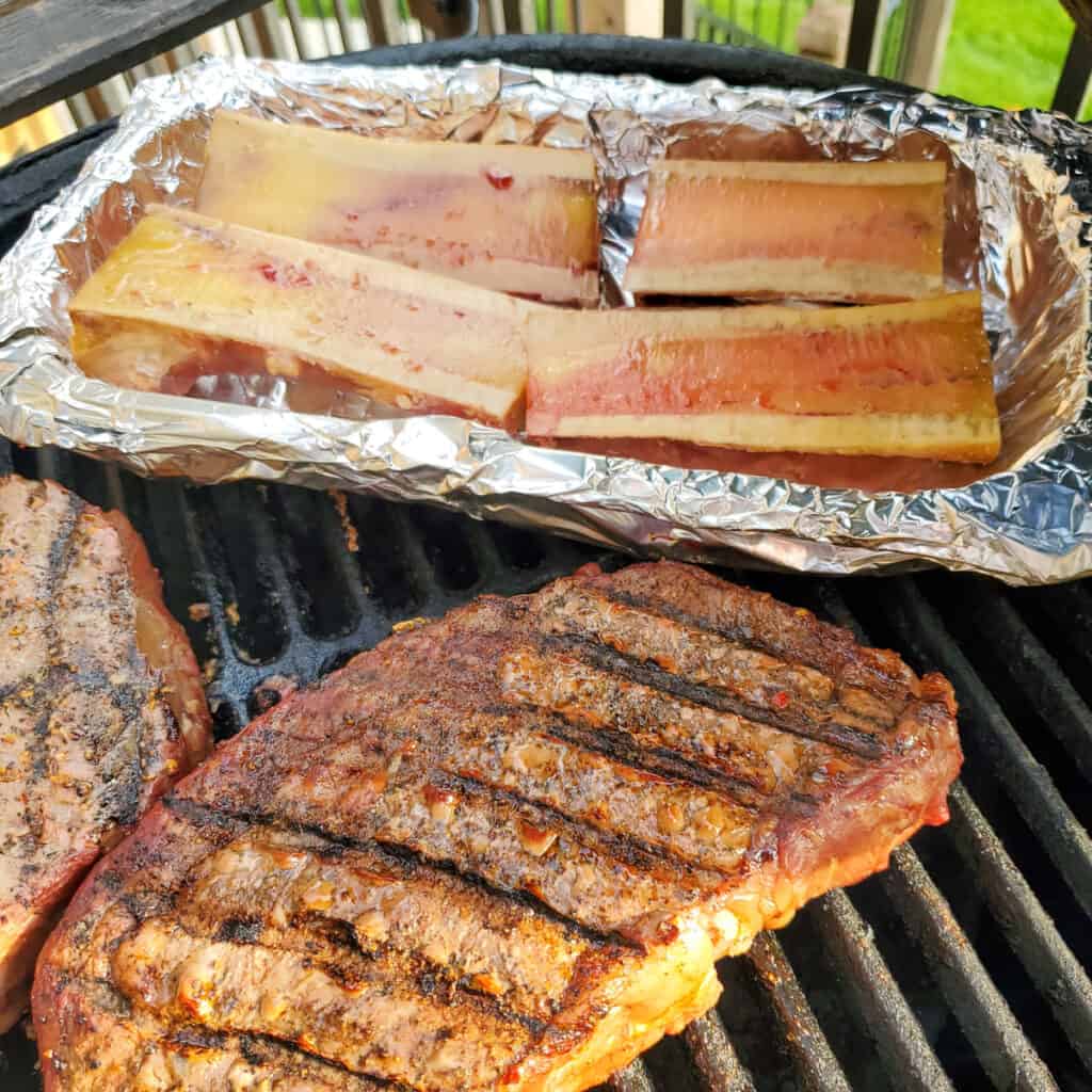 Bone marrow and steak on a BBQ grill.