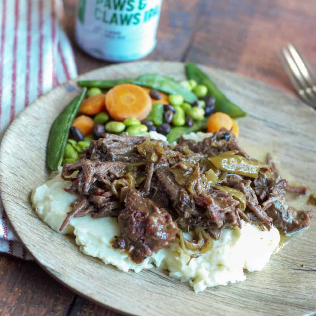 Plate of Over the Top Mississippi Pot Roast served over mashed potatoes with vegetables.