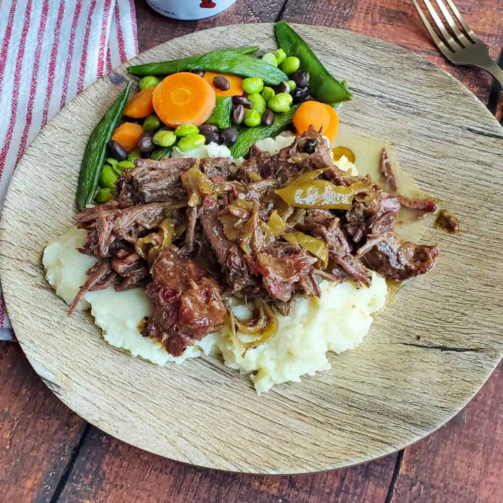 Over the Top Mississippi Pot Roast served over mashed potatoes with vegetables.