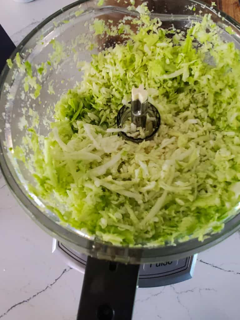 Shredded green cabbage in a food processor.