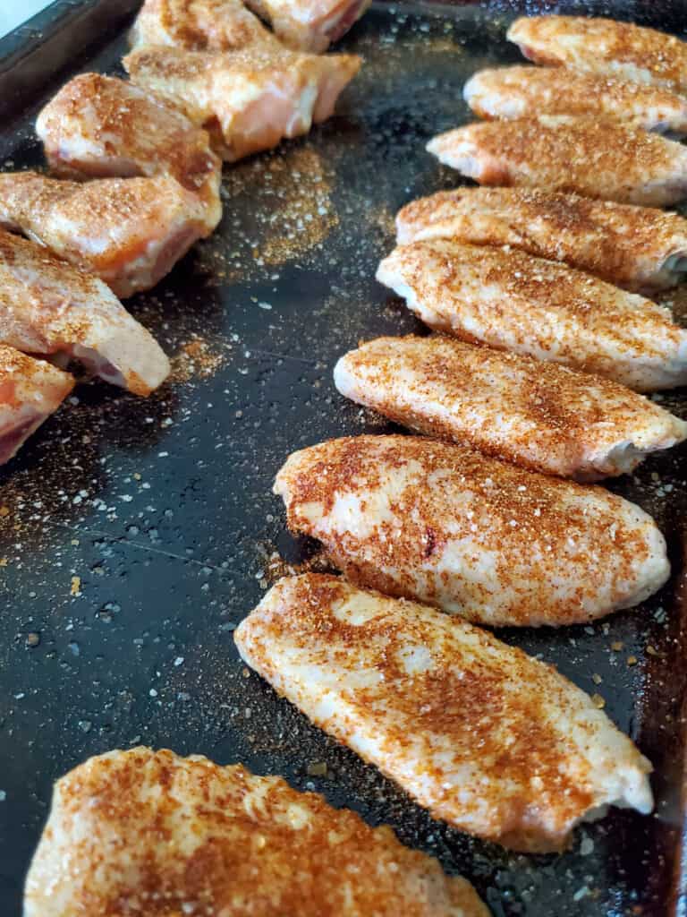 Seasoned dry rubbed chicken wings on a sheet pan.