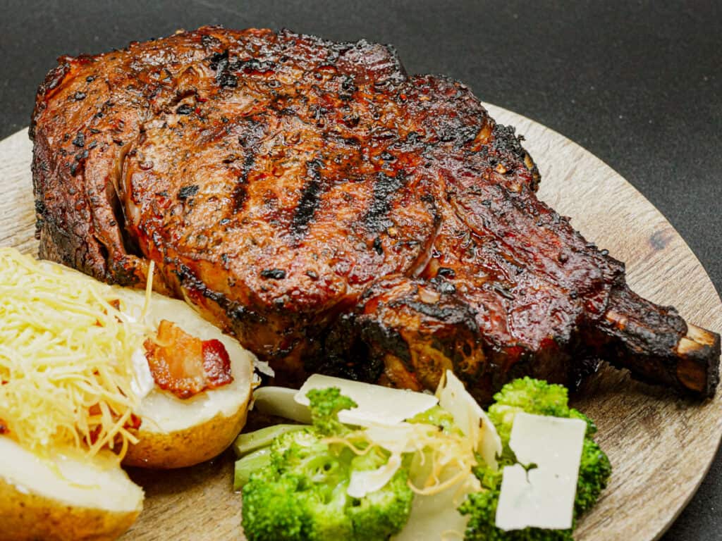 Thick cut ribeye steak served with a loaded bake potato and broccoli.