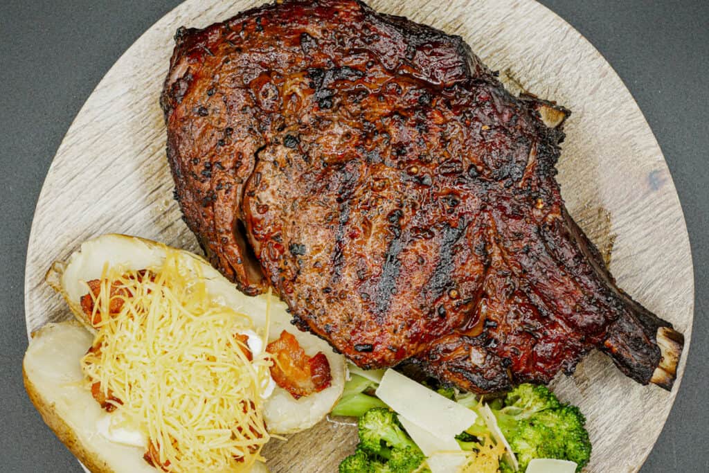 Cowboy steak seasoned with Chicago steak rub and served with broccoli and a baked potato.