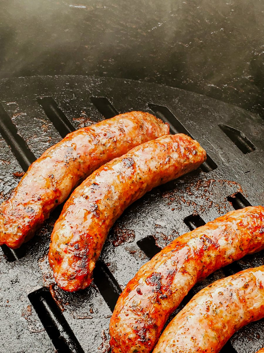 Spicy Italian sausages grilling on a barrel cooker.