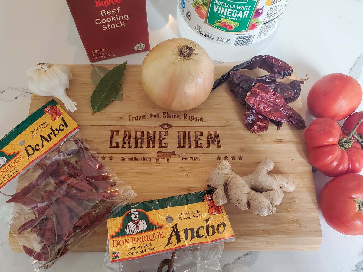Ingredients for lamb birria in a cutting board reading Carne Diem.