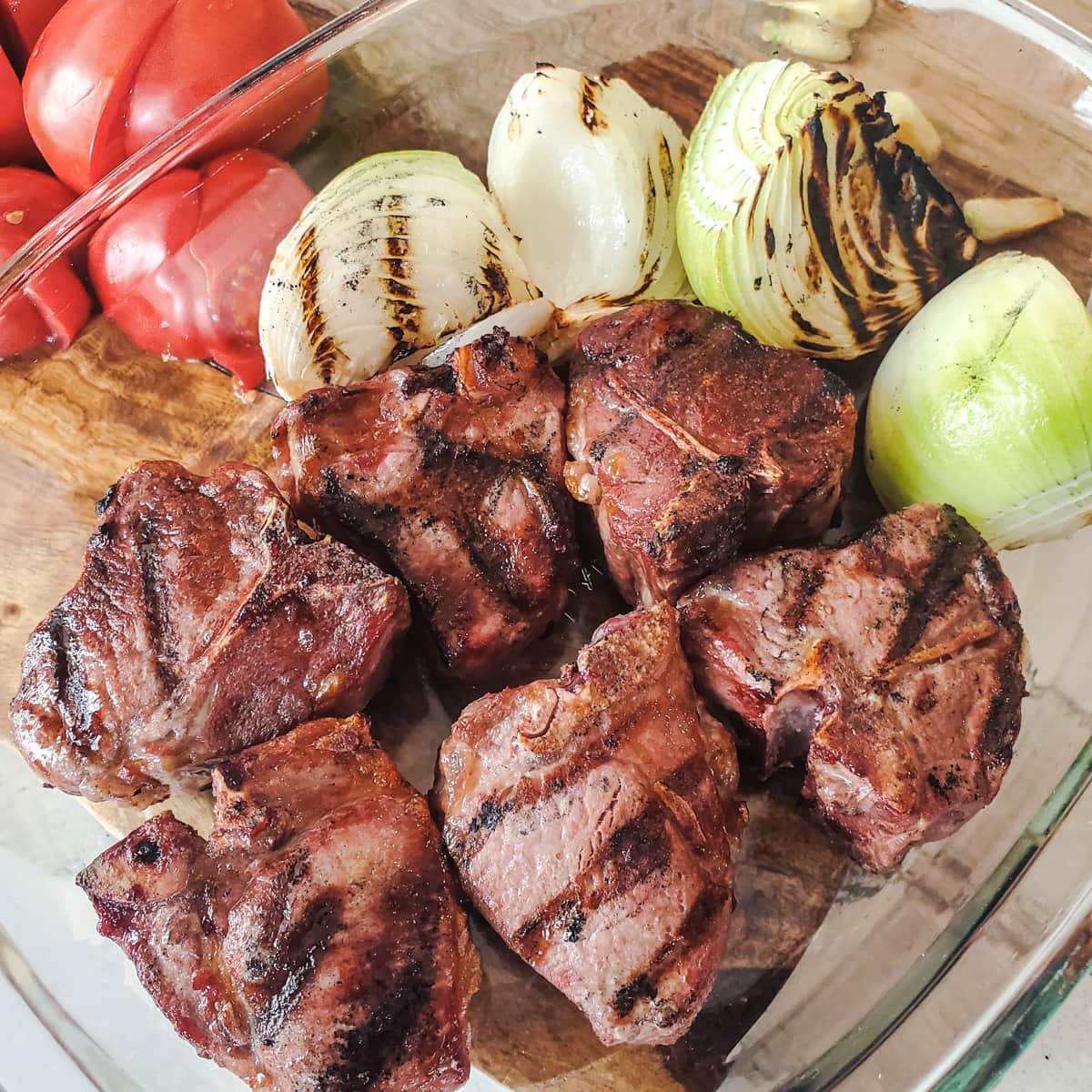 Grilled lamb chops and onions in a glass pan.