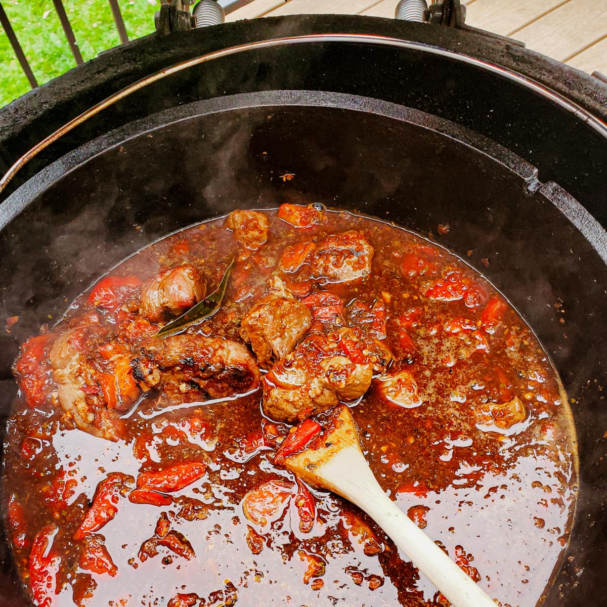 Lamb birria cooking in a Dutch oven on a Big Green Egg.