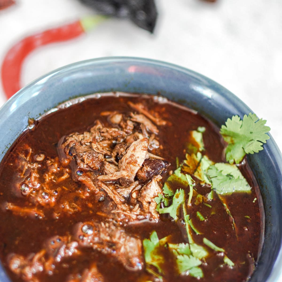 Bowl of lamb birria in a bowl topped with cilantro.