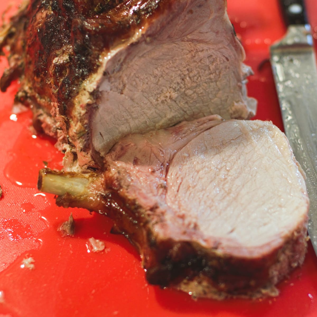 Pork roast being sliced on a cutting board.