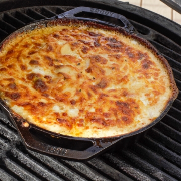 Smoked Au Gratin Potatoes in a cast iron skillet on a Big Green Egg smoker.