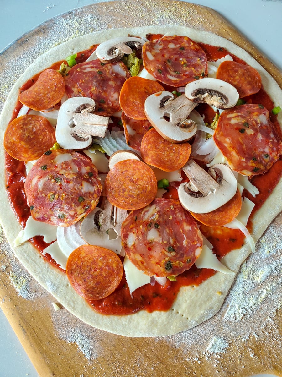 Tin crust pizza dough topped with pepperoni, salami, mushrooms, onion, and green bell pepper.