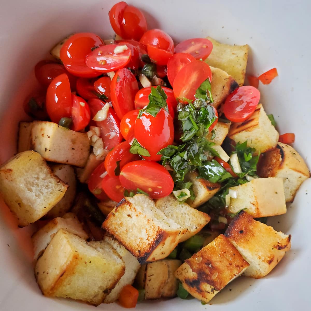 Mixing together the panzanella salad in a bowl.