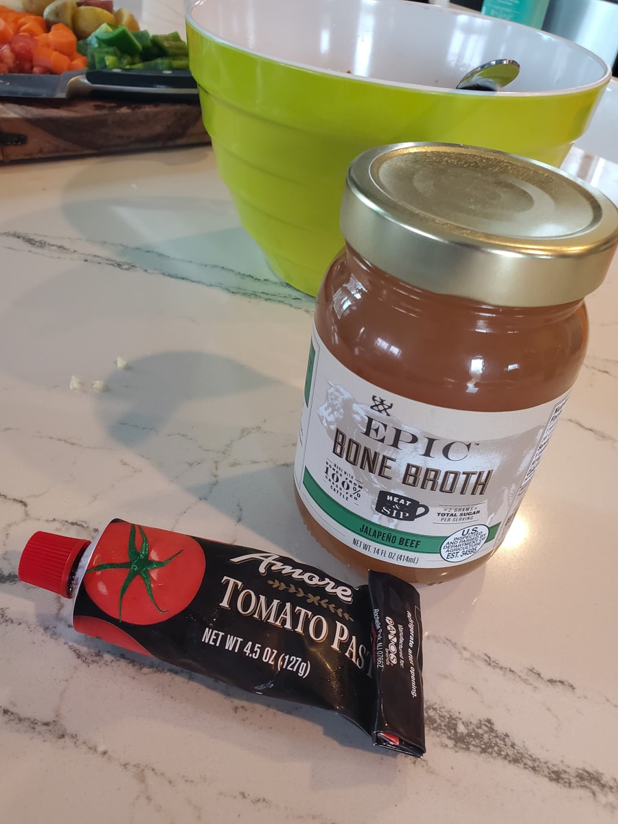 Beef broth and tomato paste on a countertop. 