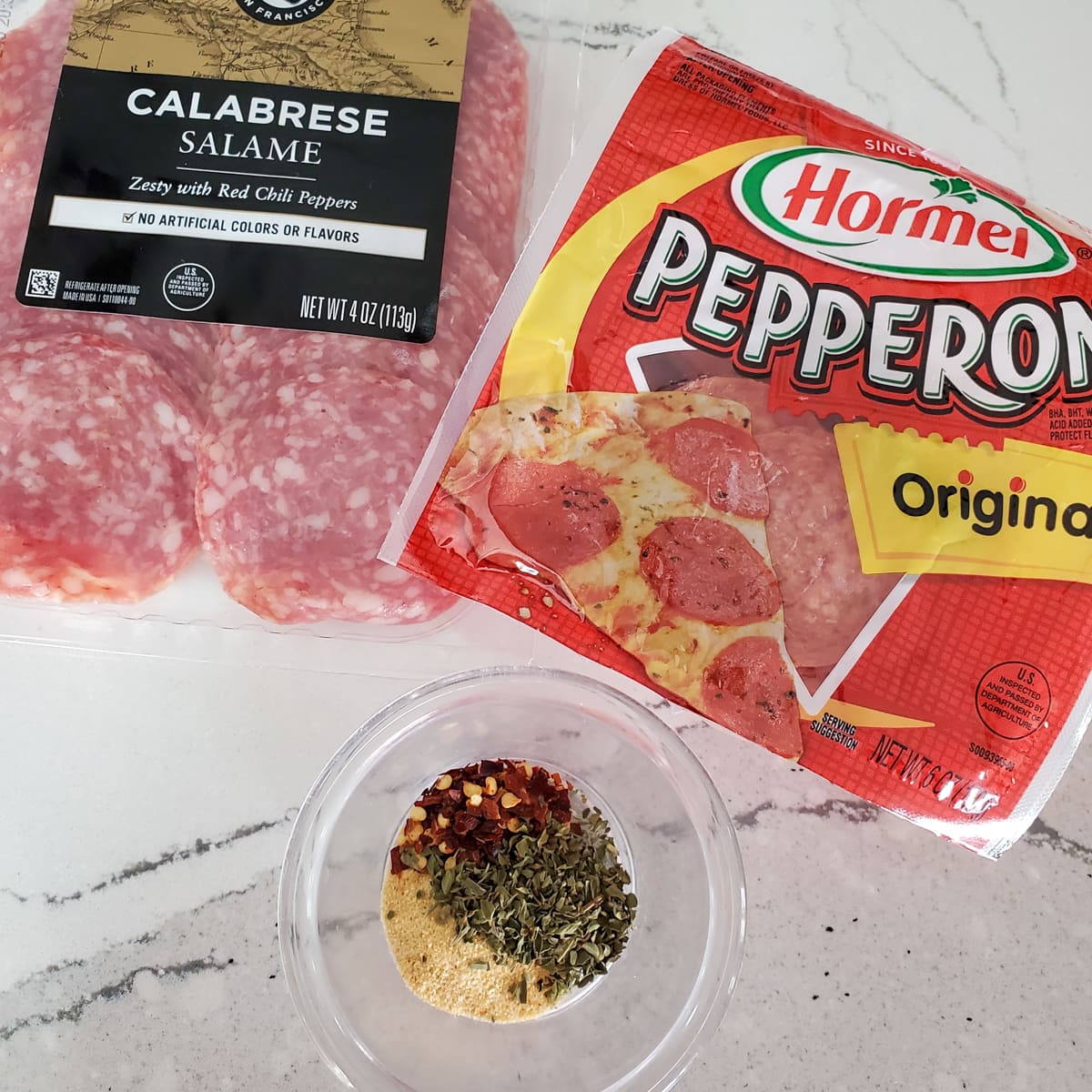 Seasoning, pepperoni, and calabrese salami on a table.