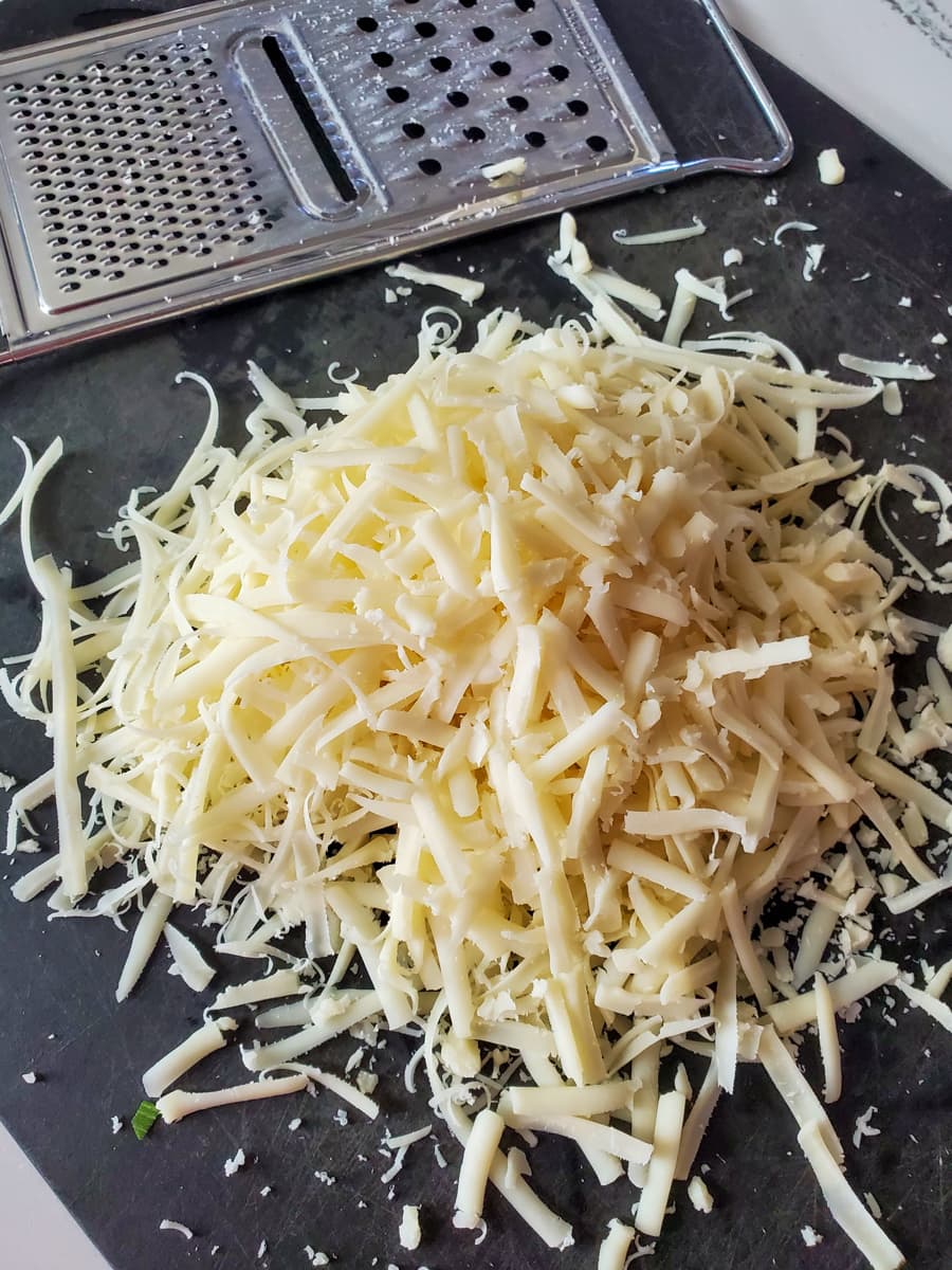 Shredded mozzarella cheese on a cutting board.