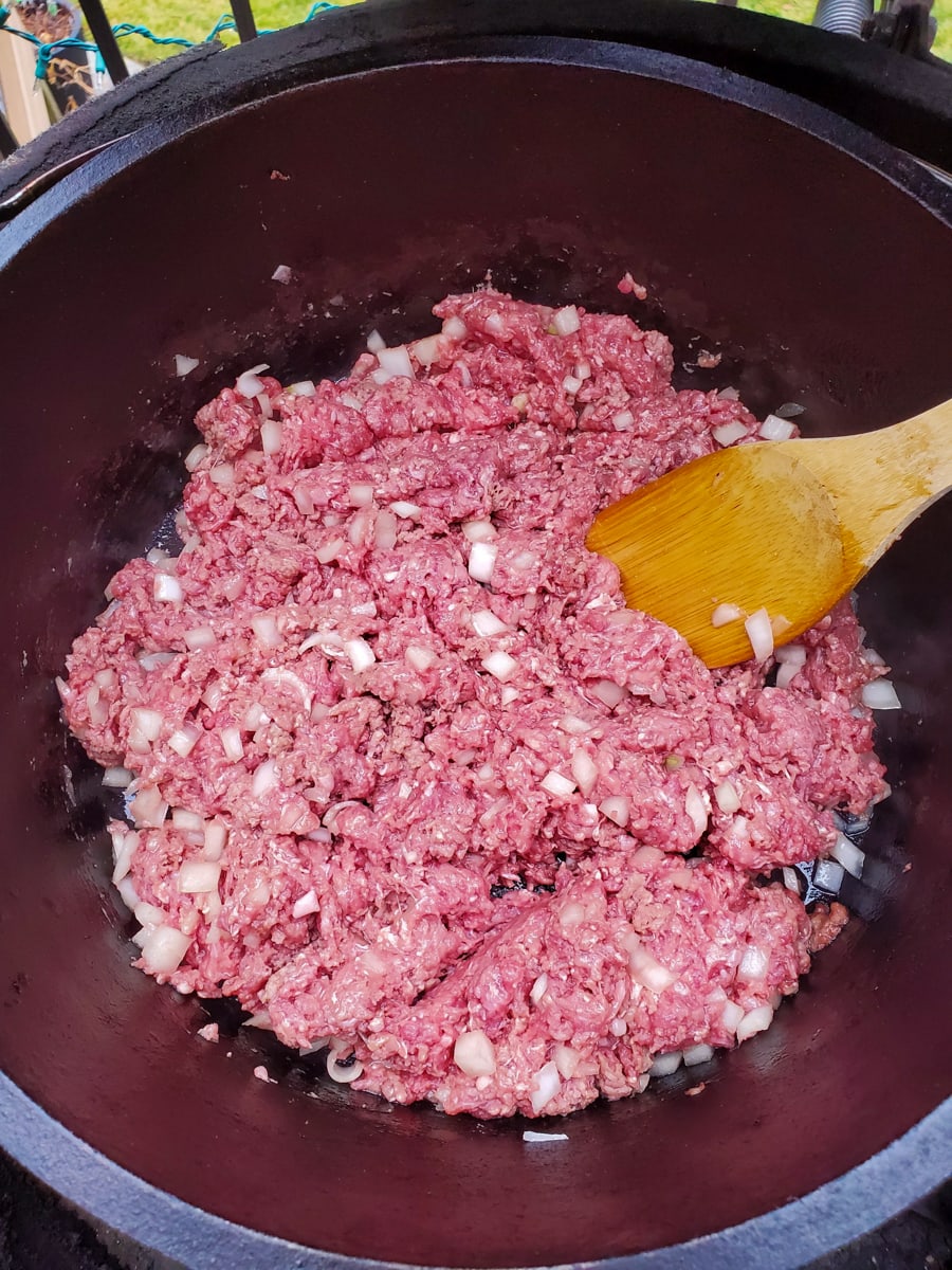 Ground beef and onion cooking in a Dutch oven.