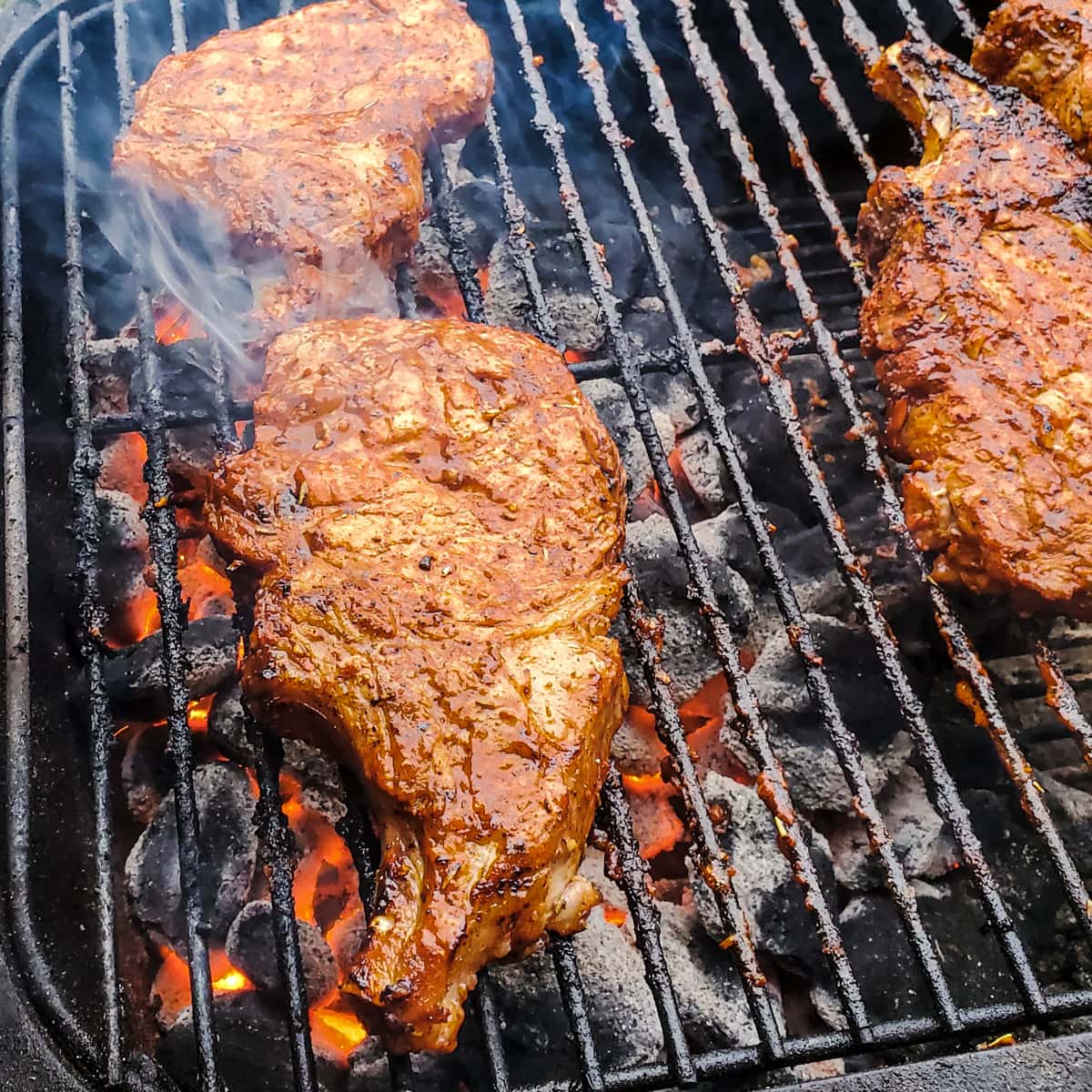 Tomahawk Pork Chops grilling on a PK Grill.