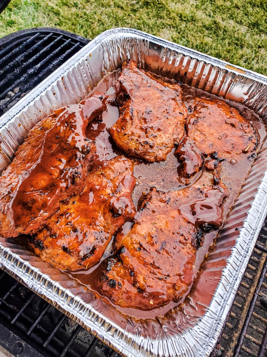 Grilled Kansas City pork chops simmering in beer and BBQ sauce.