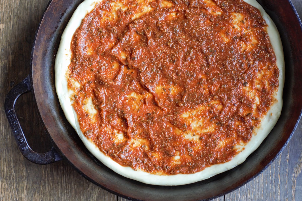 The best homemade pizza sauce spread on a pan pizza,